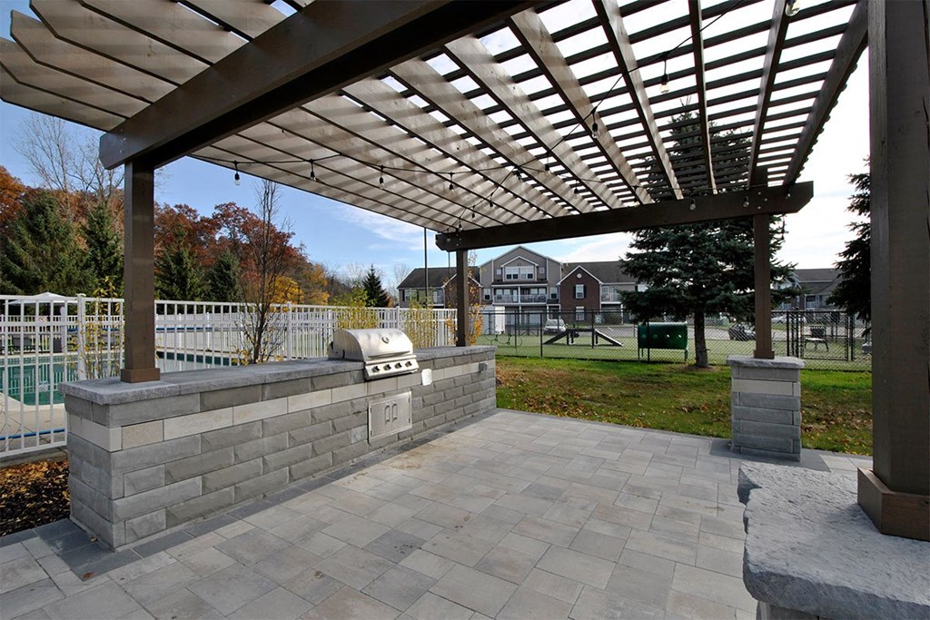 a patio with a stone retaining wall and a pergola