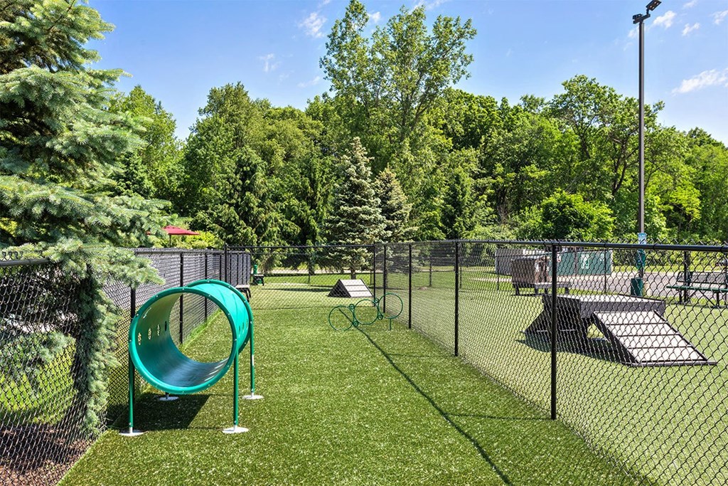 a fenced in play area with a playground and a swing set