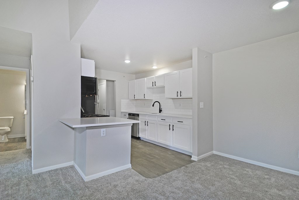 an empty kitchen with white cabinets and a white counter top