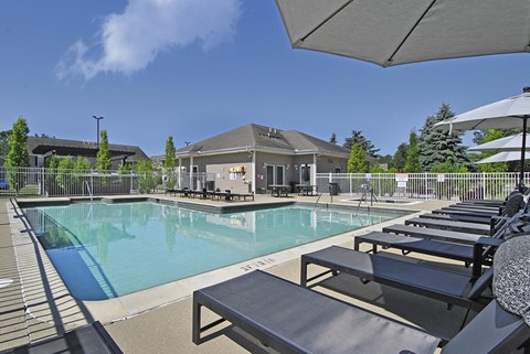 A pool with sun loungers and a building in the background.