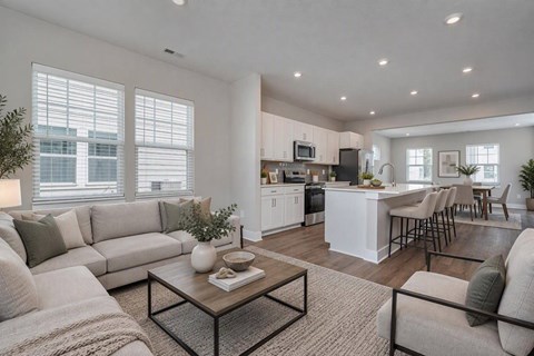 A modern living room with a kitchen in the background.