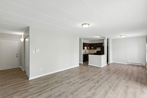 A spacious room with wooden flooring and white walls.