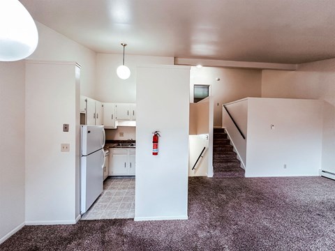 A kitchen area with a refrigerator, cabinets, and a stove top oven.