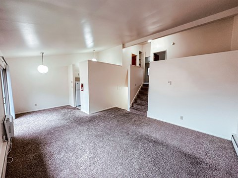 A large empty room with a staircase and a fire extinguisher.