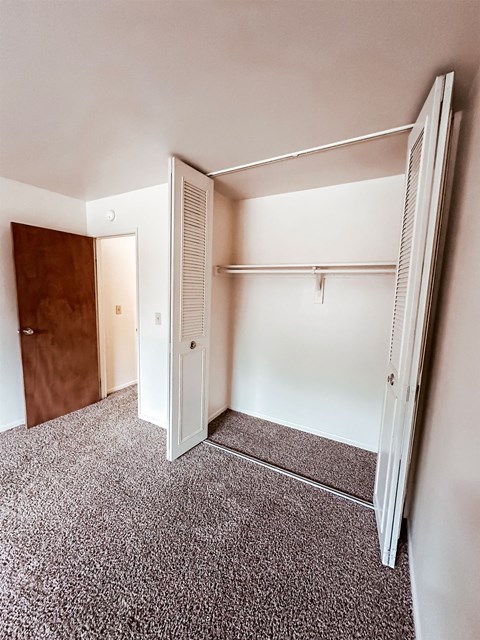 A white closet with a brown door is open.