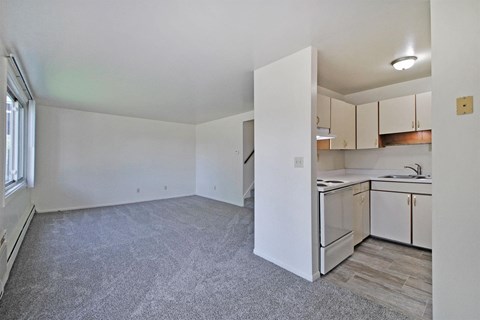 the spacious living room and kitchen with white cabinets and white appliances