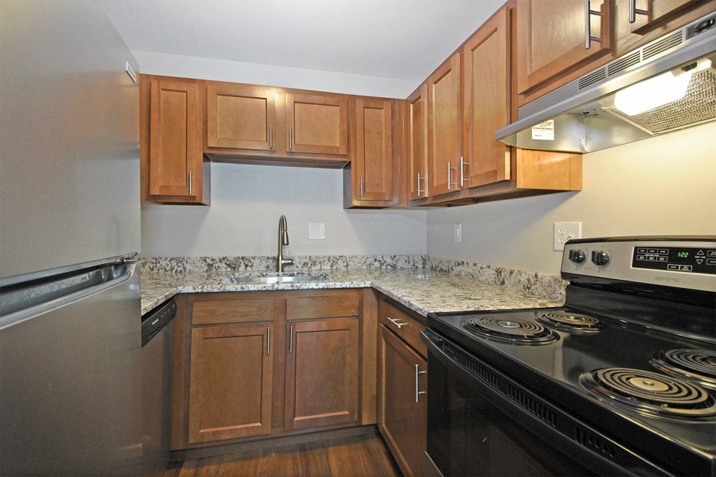 an empty kitchen with wood cabinets and black appliances