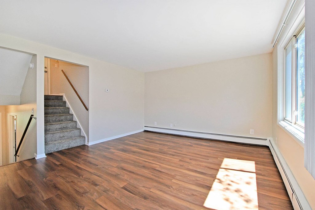 an empty living room with wood flooring and a staircase