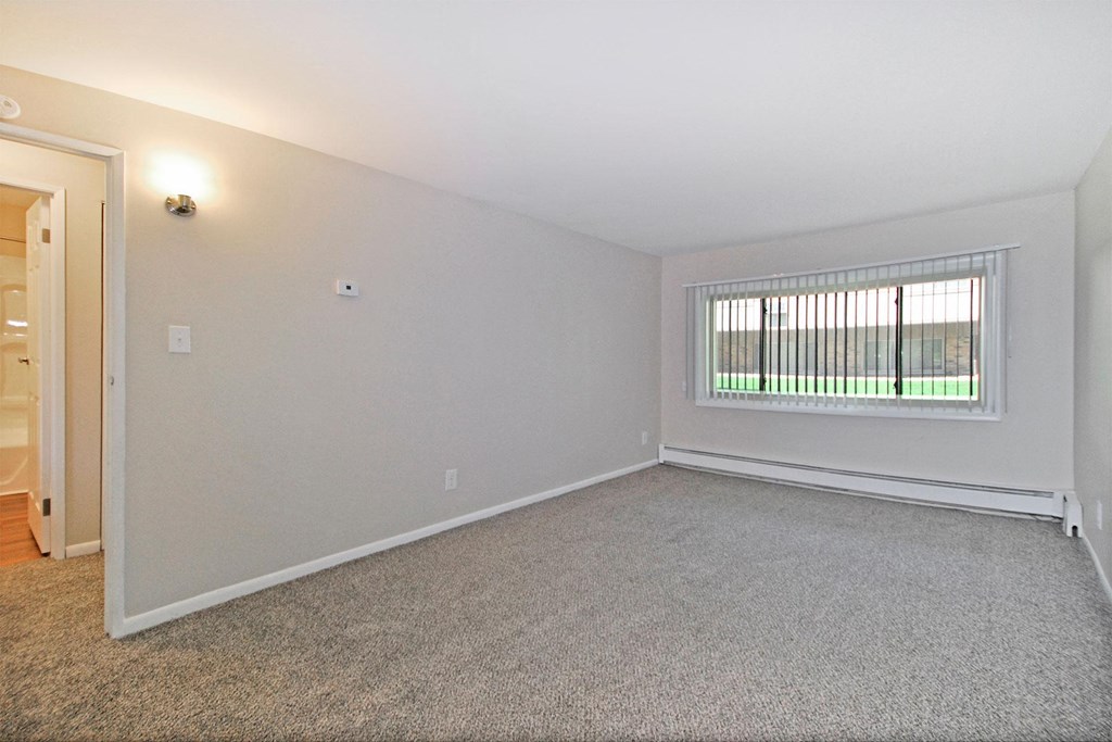 the spacious living room of an empty home with a window