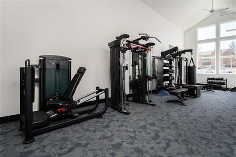 A gym with a variety of exercise equipment including treadmills, stationary bikes, and weight machines.
