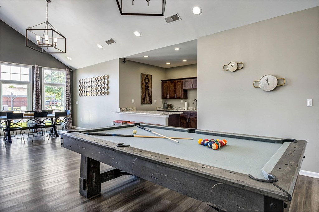 a pool table in a clubhouse with a bar and a kitchen