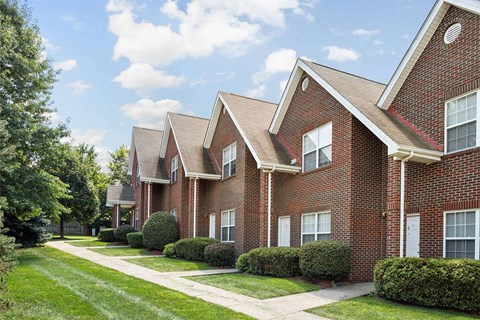 a sidewalk in front of a brick apartment building