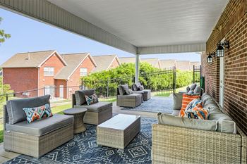 a covered patio with furniture and a brick wall