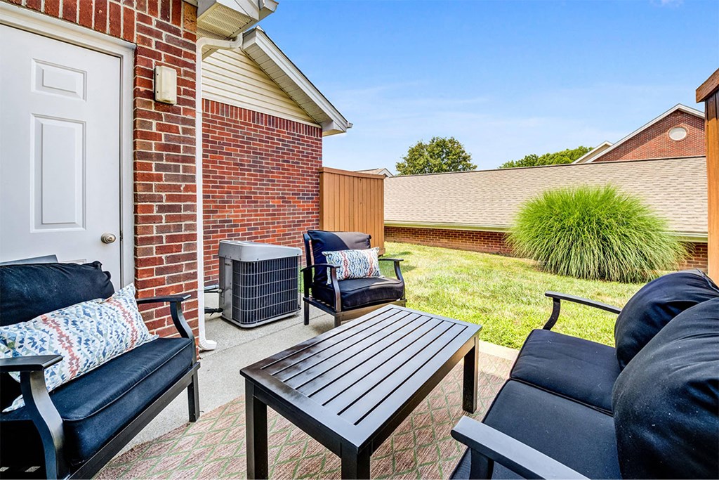 a patio with chairs and a table in front of a house