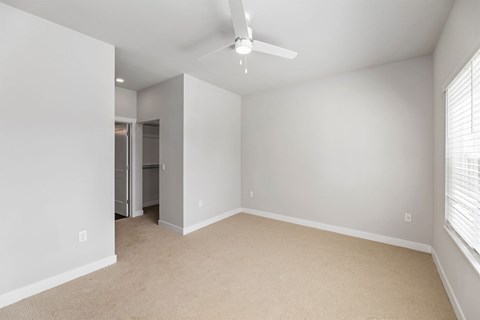 A room with a ceiling fan and carpeted floor.