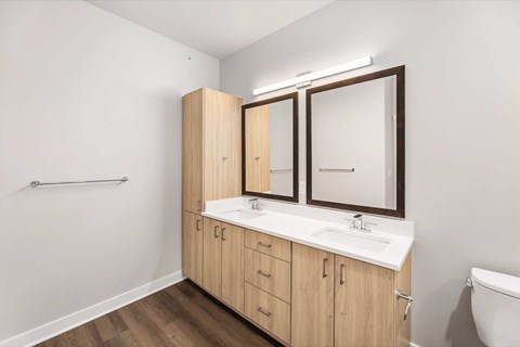 A bathroom with a white sink and wooden cabinets.