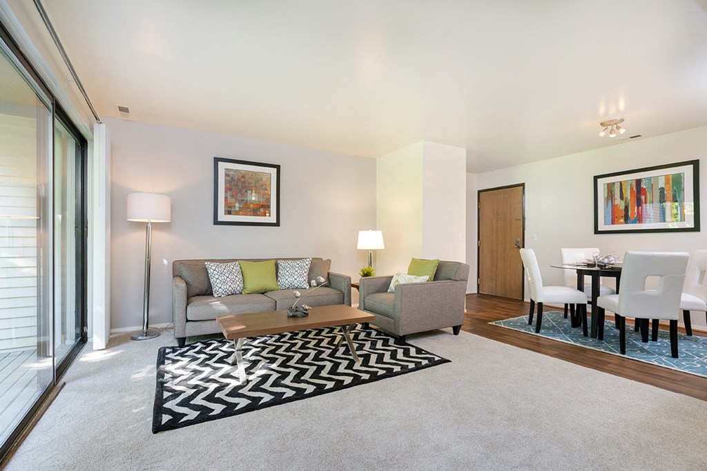 a living room with a couch and a rug and a dining room table
