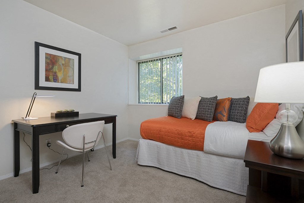 a bedroom with an orange bed and a desk with a chair