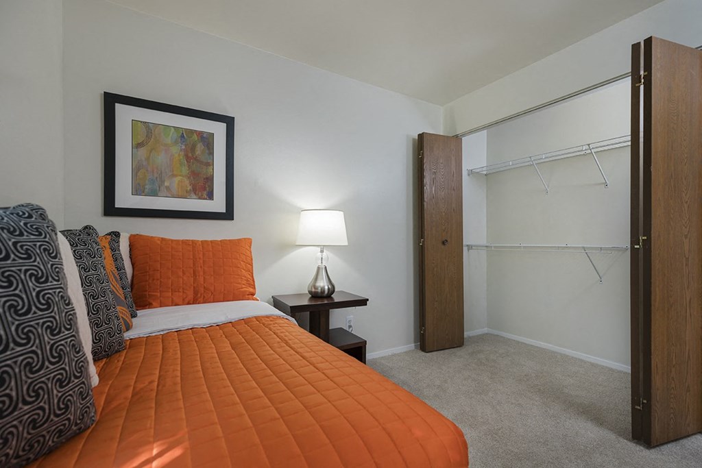 a bedroom with an orange bed and a closet