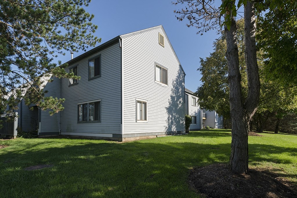 the exterior of a white house with a yard and trees