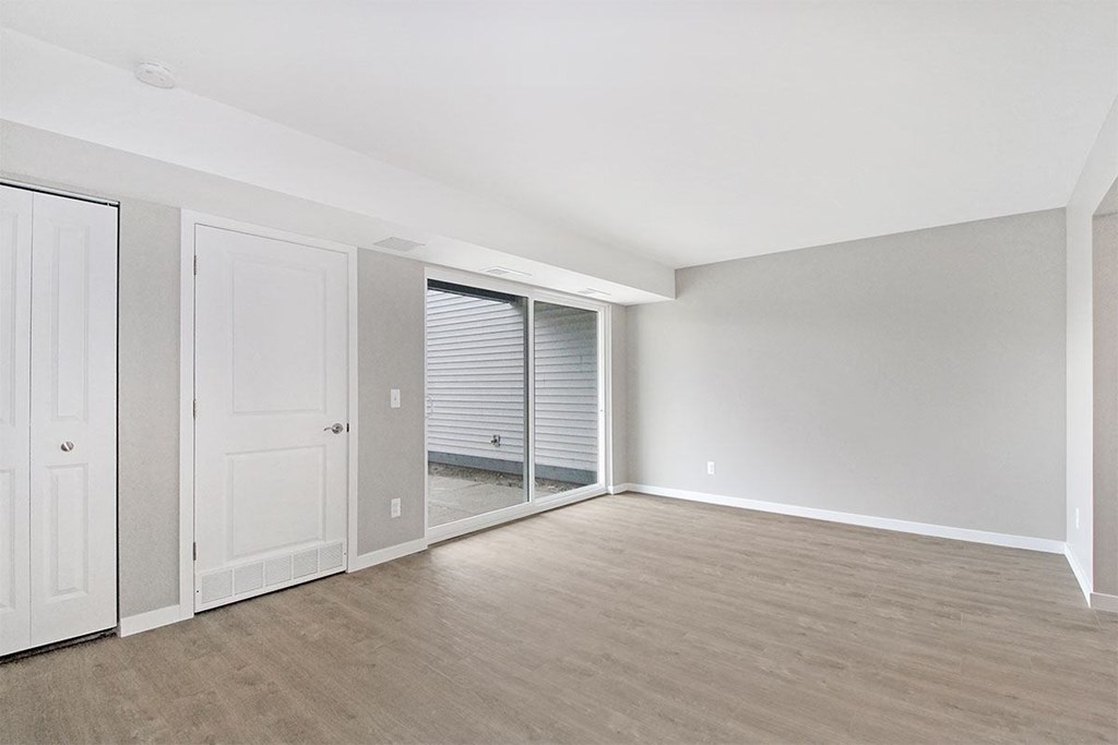 an empty living room with a sliding glass door to a closet