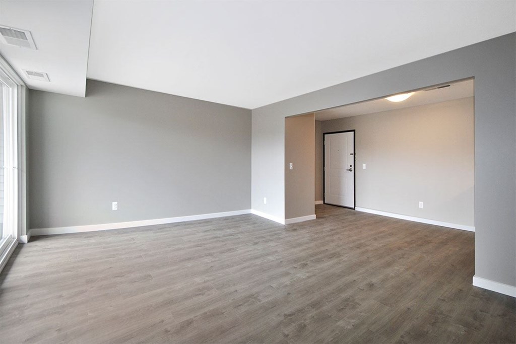 the living room and dining room of an empty home with wood flooring