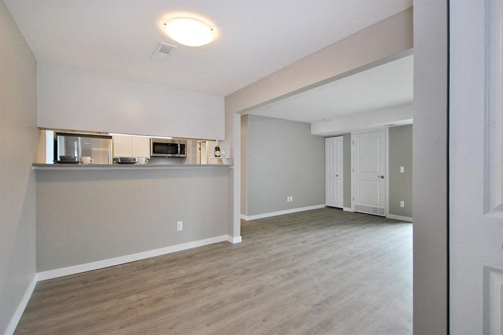 an empty living room and kitchen with wood flooring