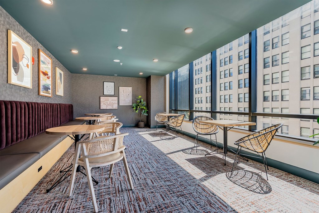 a lounge area with tables and chairs and a large window