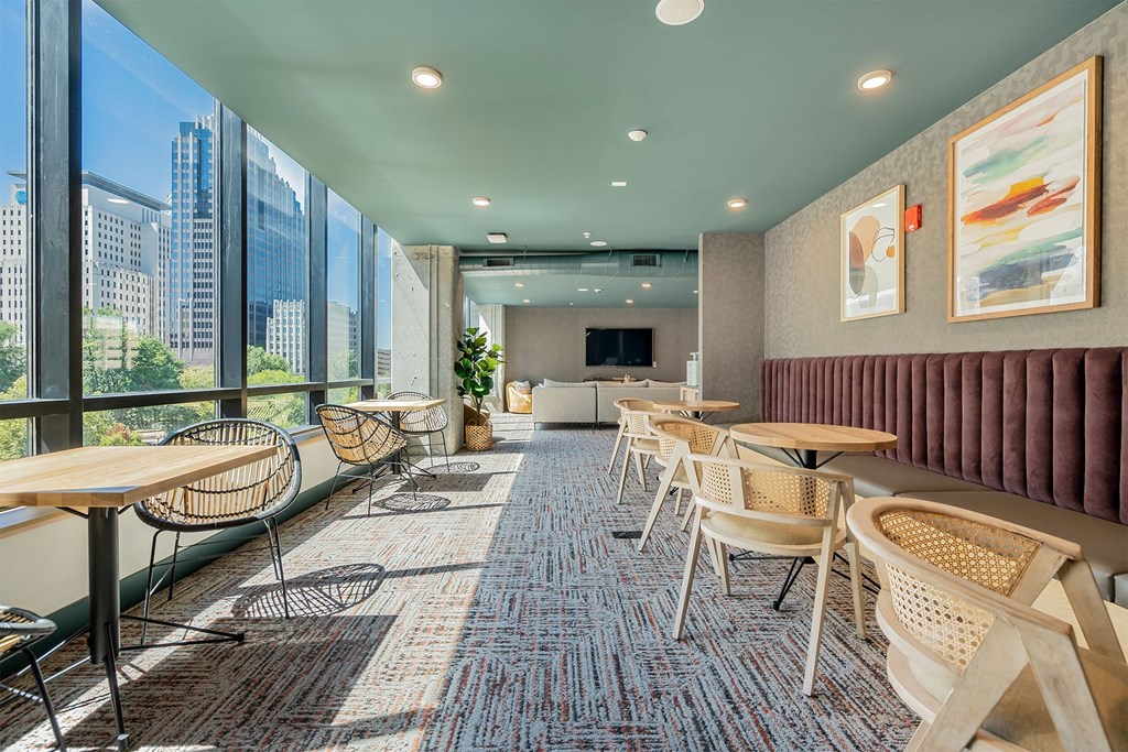 a lounge area with tables and chairs and a large window