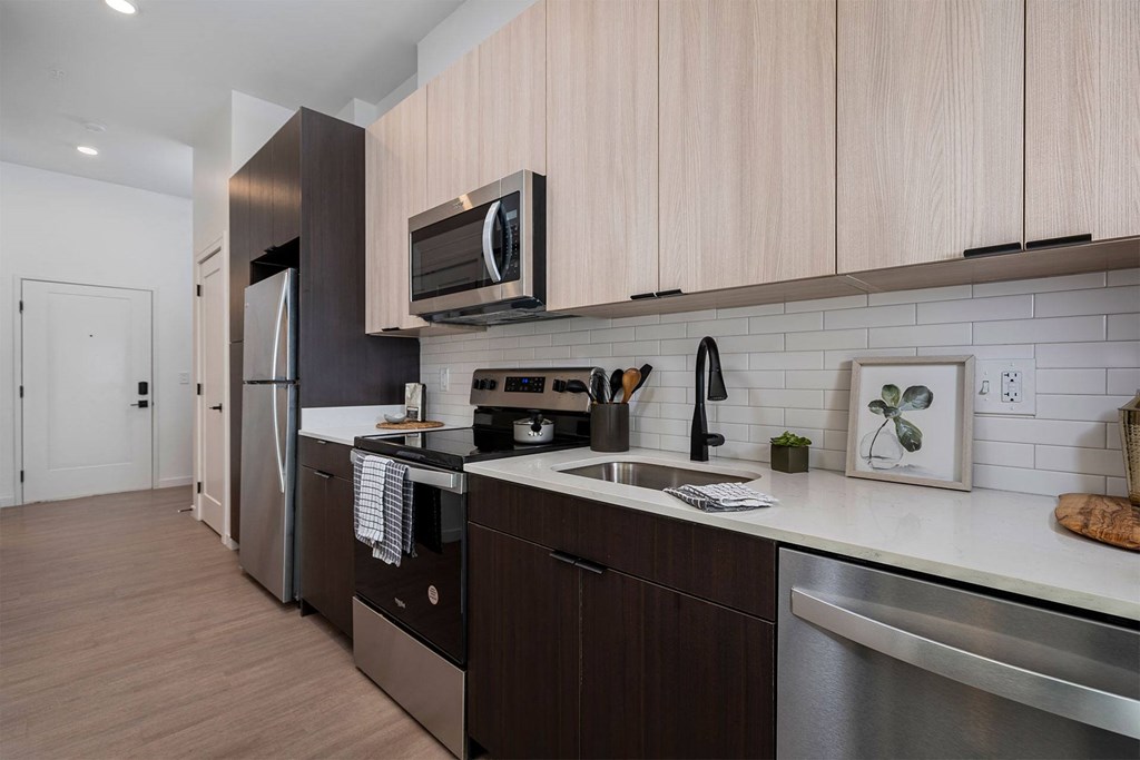 modern kitchen with light wood top cabinets dark bottom cabinets and stainless steel appliances