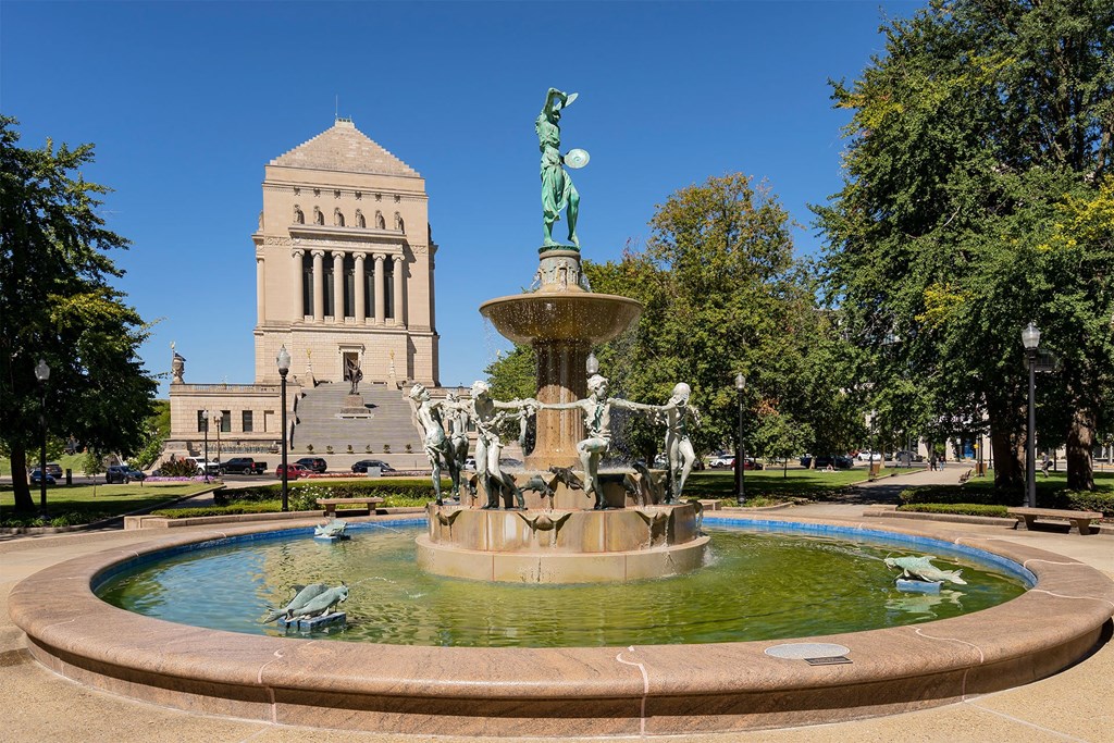 a fountain in a park with a building in the background