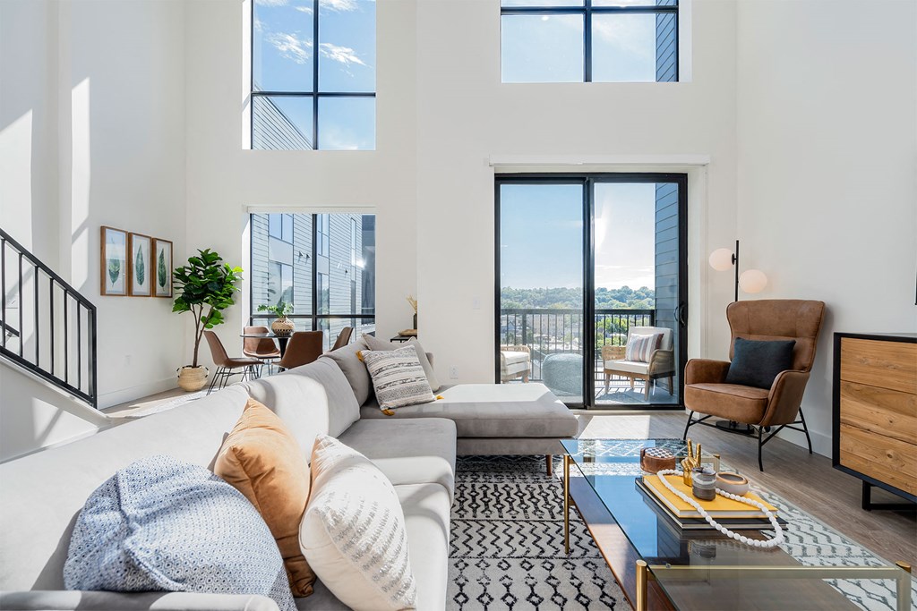 an open living room with a large white couch and a balcony