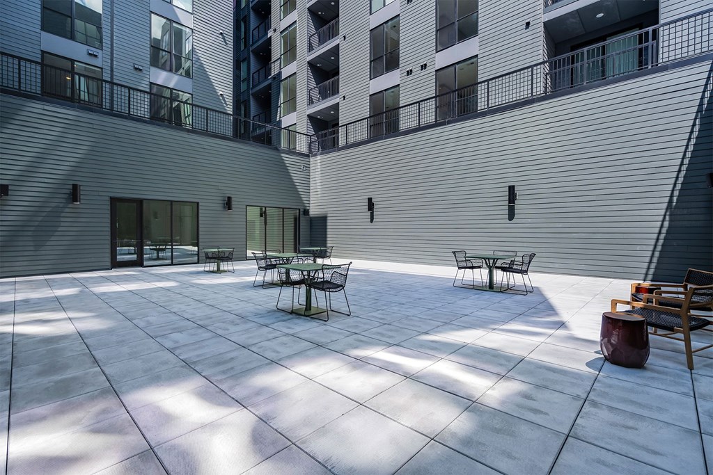 an open courtyard with tables and chairs in front of an apartment building