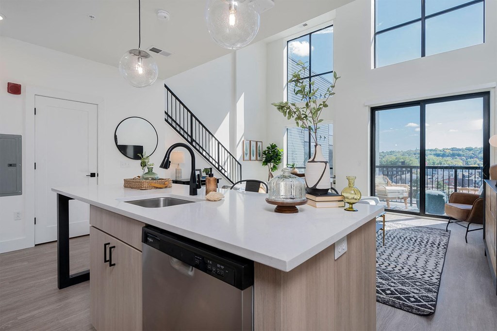 an open kitchen with a view of a living room and a staircase