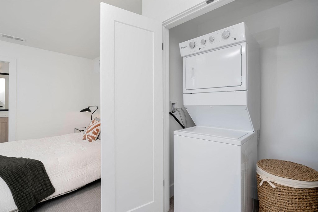 a white washer and dryer in a bedroom with a bed