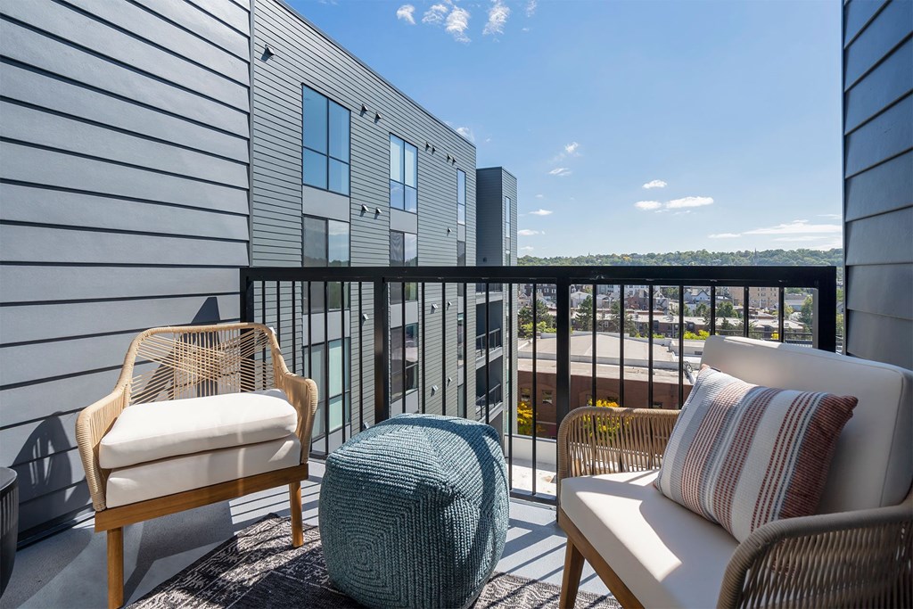 a furnished balcony with chairs and a view of the city