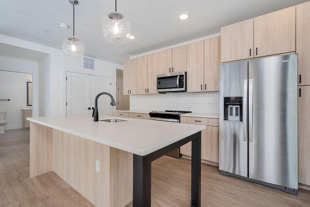 a kitchen with a large island and a stainless steel refrigerator