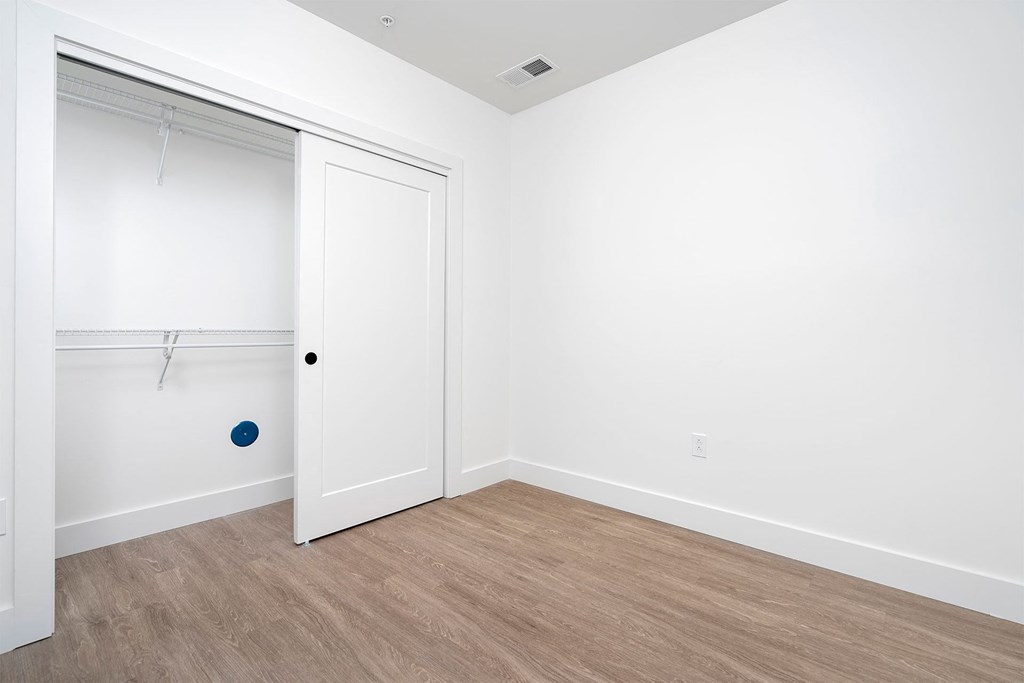 a bedroom with a door to a closet and a wood floor