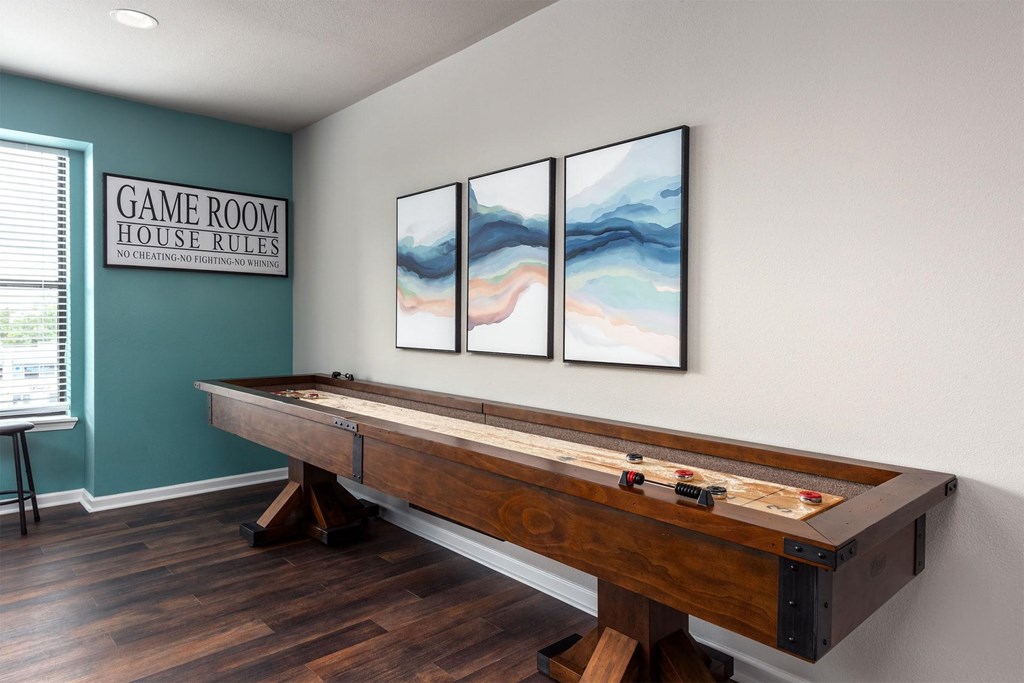 a game room with a pool table and three paintings on the wall