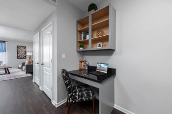 a home office with a desk and a door to a living room