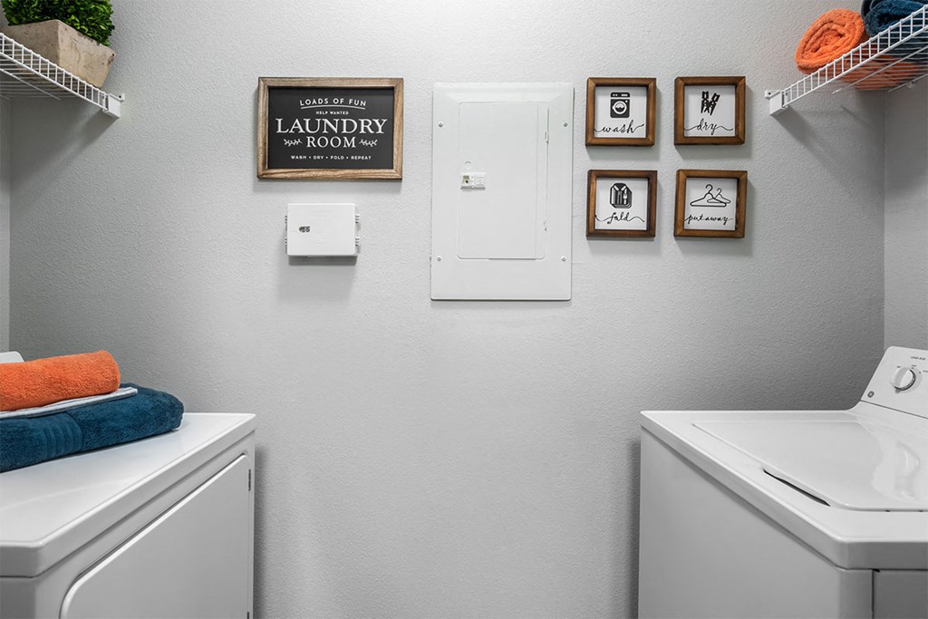 a washer and dryer in a laundry room with pictures on the wall