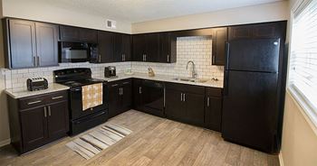 a kitchen with black cabinets and a wood floor