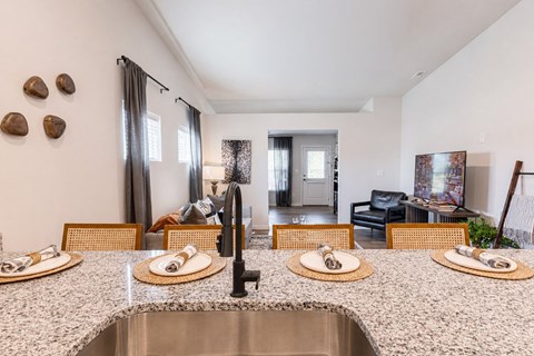 A kitchen with a sink and a dining table set for two.