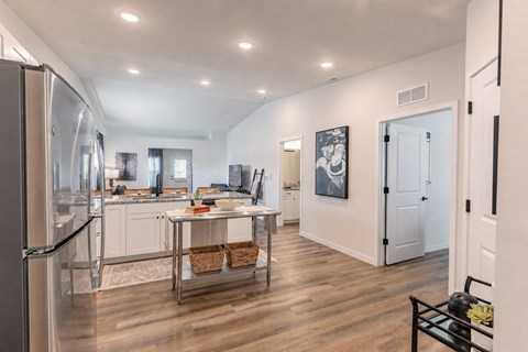 A kitchen with a refrigerator on the left and a dining table in the middle.