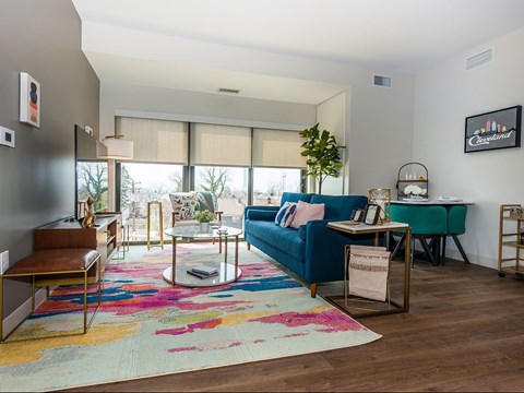A living room with a blue couch and a colorful rug.