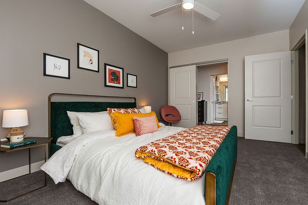 A bedroom with a bed, nightstand, and a ceiling fan.