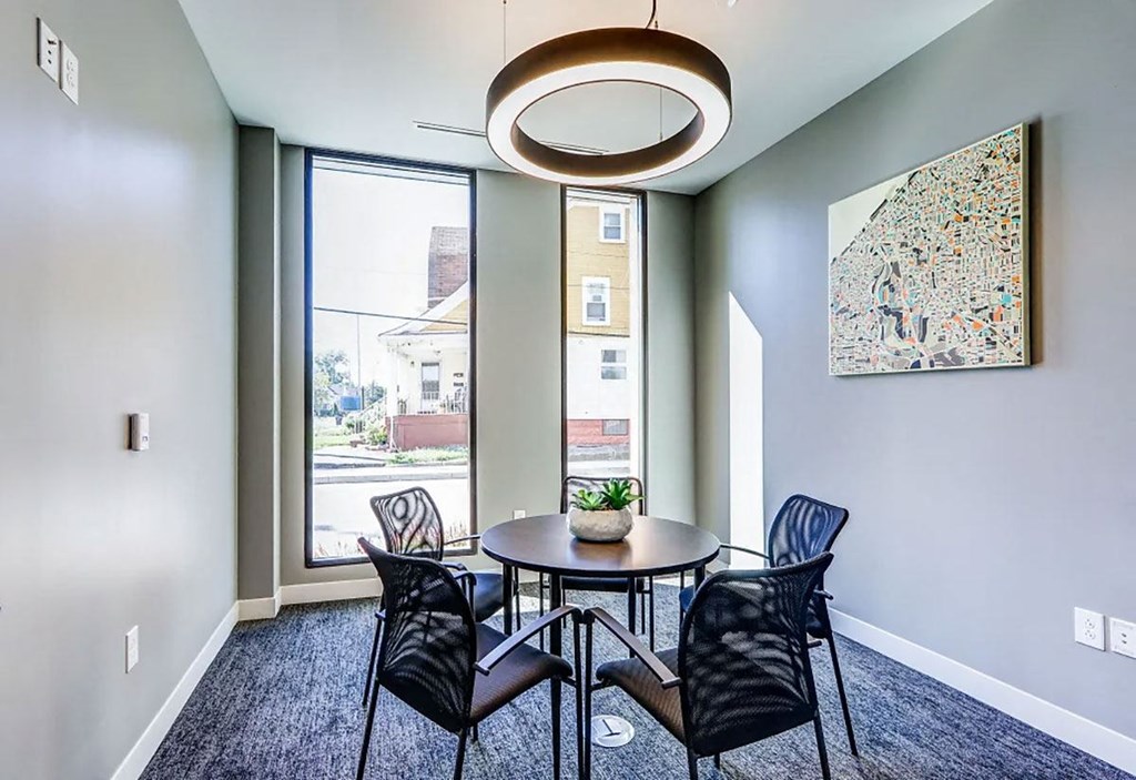 A room with a table and chairs and a painting on the wall.
