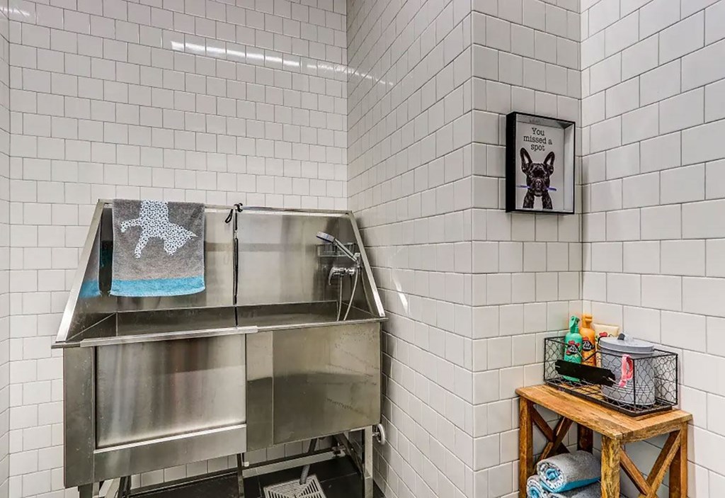 A kitchen area with a stainless steel sink and a wooden table with various items on it.