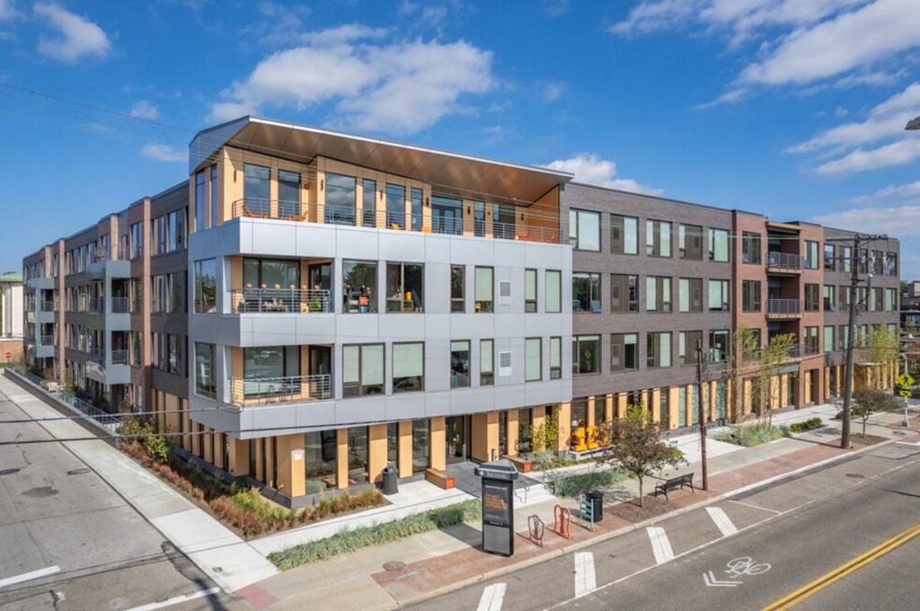 A modern multi-story building with a mix of glass and solid panels.