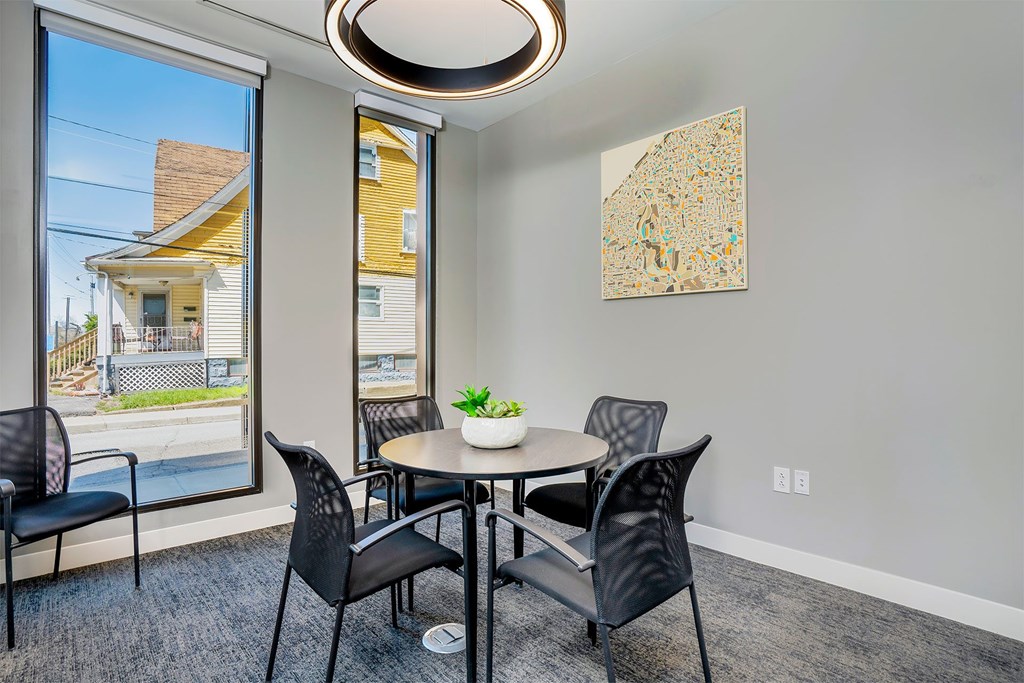 A dining room with a table and chairs and a painting on the wall.